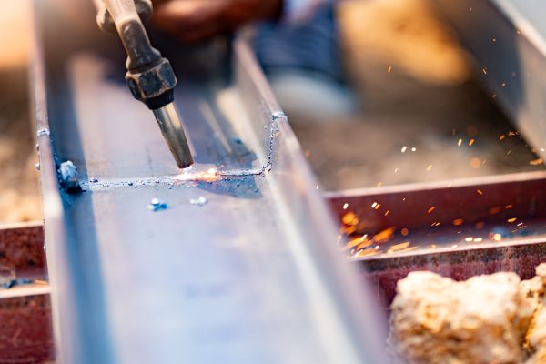 Skilled labor and craftsmanship in metal fabrication. Use of torches for cutting metal. Safety measures and personal protective equipment for metalworkers. Precision and accuracy in metal cutting.